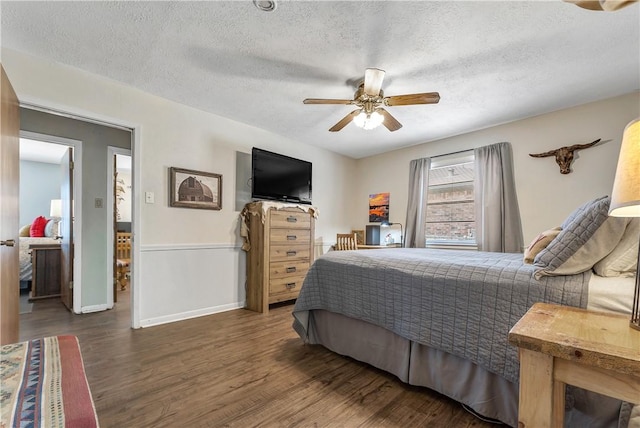 bedroom with ceiling fan, dark hardwood / wood-style floors, and a textured ceiling