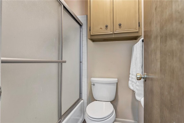 bathroom featuring combined bath / shower with glass door and toilet