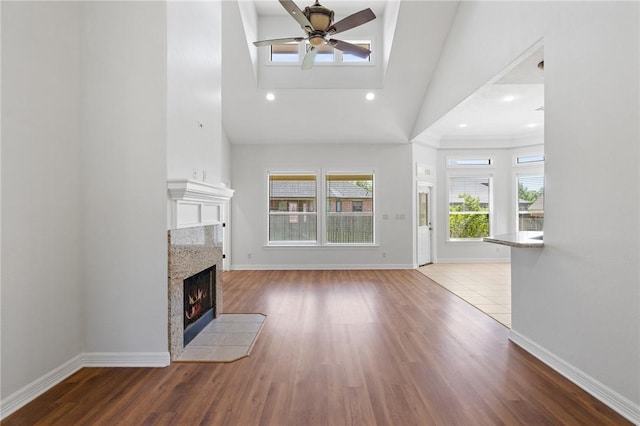 4412 Hearst Ct, College Station, TX 77845 - unfurnished living room with a ceiling fan, high vaulted ceiling, a high end fireplace, wood finished floors, and baseboards