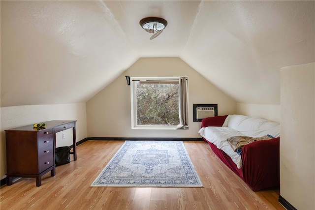 bonus room featuring vaulted ceiling, a wall mounted air conditioner, and light hardwood / wood-style floors