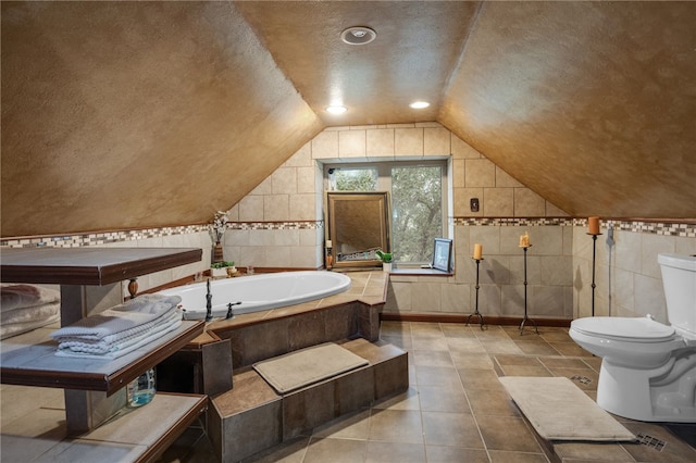 bathroom featuring toilet, vaulted ceiling, a textured ceiling, a relaxing tiled tub, and tile patterned flooring