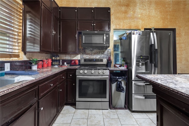 kitchen featuring tasteful backsplash, appliances with stainless steel finishes, dark brown cabinets, and light tile patterned floors