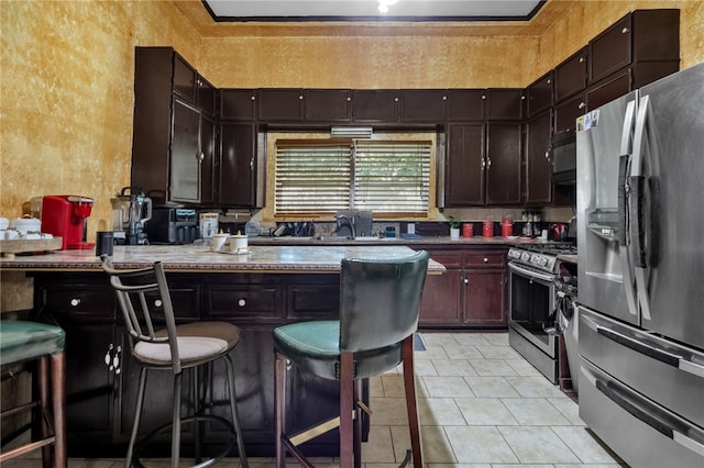 kitchen with stainless steel appliances, light tile patterned flooring, dark brown cabinets, and a breakfast bar