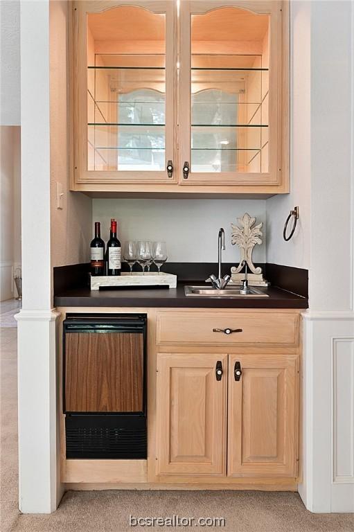 bar featuring sink, light colored carpet, and light brown cabinets