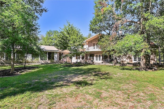 view of yard featuring french doors and a balcony