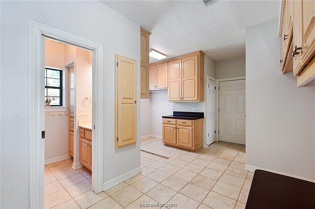 kitchen with light brown cabinetry, a textured ceiling, and light tile patterned floors