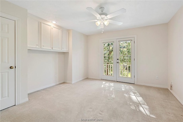 carpeted spare room featuring ceiling fan and french doors