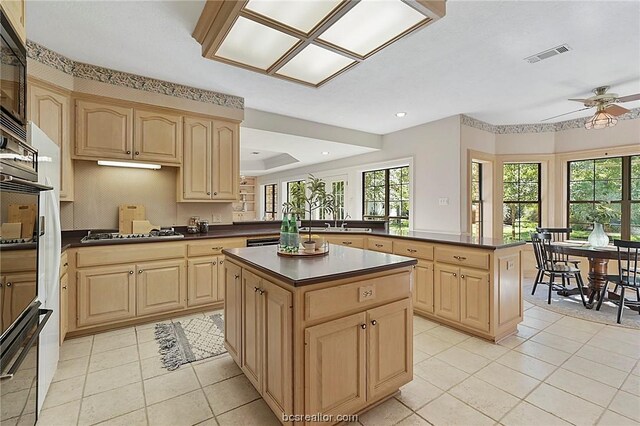 kitchen with ceiling fan, a center island, a healthy amount of sunlight, and light brown cabinetry