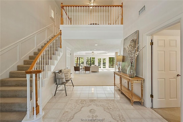 foyer entrance with ceiling fan, light carpet, and french doors