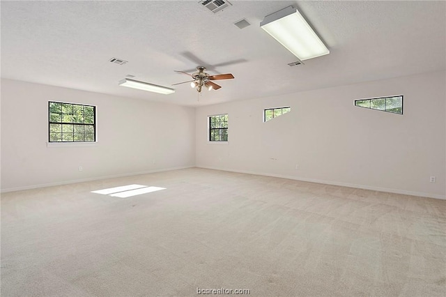 spare room featuring a textured ceiling, light colored carpet, and ceiling fan