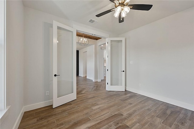 7888 Mathis Creek Dr, Bryan, TX 77808 - empty room with french doors, a chandelier, ceiling fan, wood finished floors, and baseboards