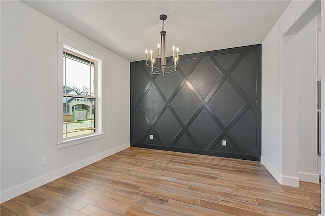 7888 Mathis Creek Dr, Bryan, TX 77808 - spare room featuring a chandelier, baseboards, light wood-type flooring, and a decorative wall