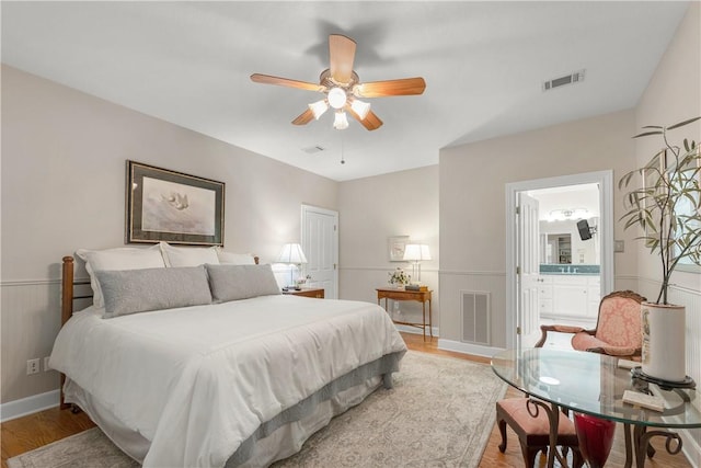 bedroom featuring ceiling fan, ensuite bathroom, and light wood-type flooring