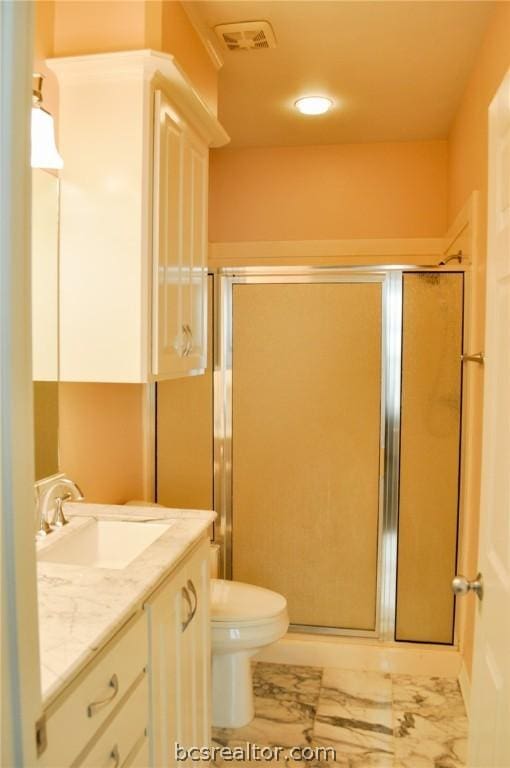 bathroom with vanity, toilet, and a shower with door