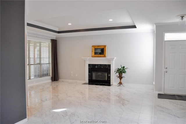 living room featuring ornamental molding, a high end fireplace, and a tray ceiling