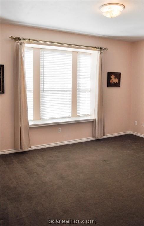 spare room with a healthy amount of sunlight and dark carpet