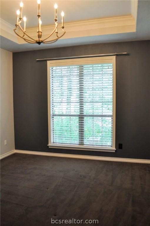 unfurnished room featuring a chandelier, a tray ceiling, plenty of natural light, and ornamental molding