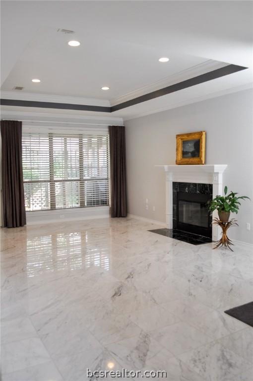 living room with crown molding, a raised ceiling, and a fireplace