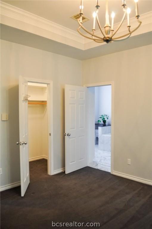 unfurnished bedroom featuring a walk in closet, dark hardwood / wood-style flooring, a chandelier, and ornamental molding