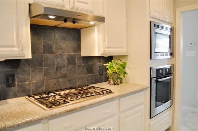 kitchen with backsplash, light stone countertops, white cabinetry, and stainless steel appliances