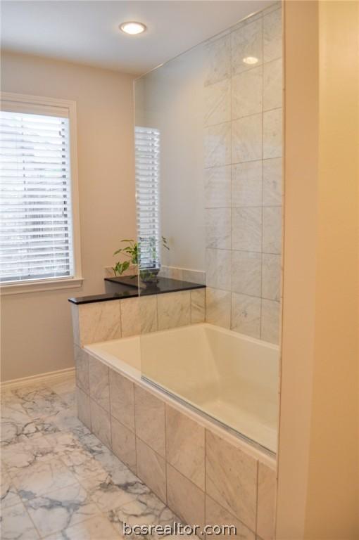 bathroom with a relaxing tiled tub