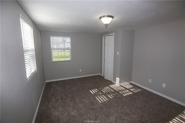 unfurnished room featuring dark colored carpet