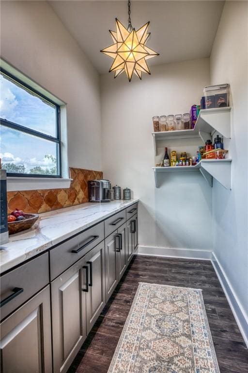 interior space with dark hardwood / wood-style flooring, hanging light fixtures, gray cabinets, a notable chandelier, and light stone counters