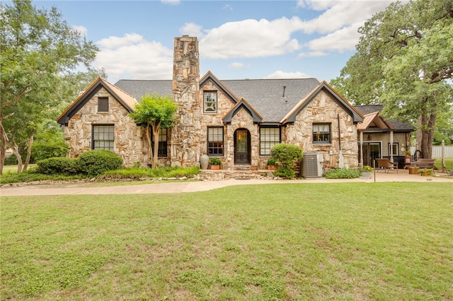 803 Meadow Ln, Bryan, TX 77802 - tudor house featuring stone siding, a chimney, a front yard, and central AC