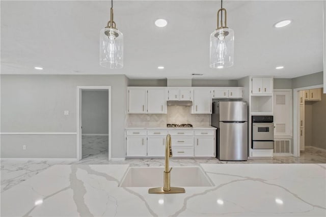 kitchen featuring a sink, marble finish floor, hanging light fixtures, appliances with stainless steel finishes, and light stone countertops