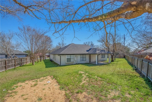 back of house featuring a lawn, a chimney, a fenced backyard, and stucco siding