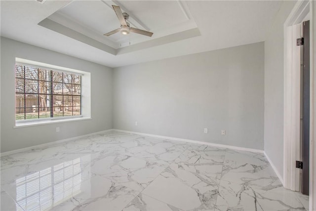 unfurnished room with a tray ceiling, marble finish floor, ceiling fan, and baseboards