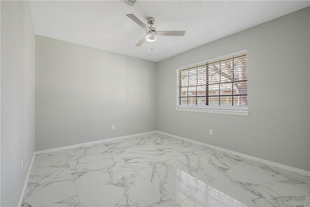 spare room featuring marble finish floor, baseboards, and a ceiling fan