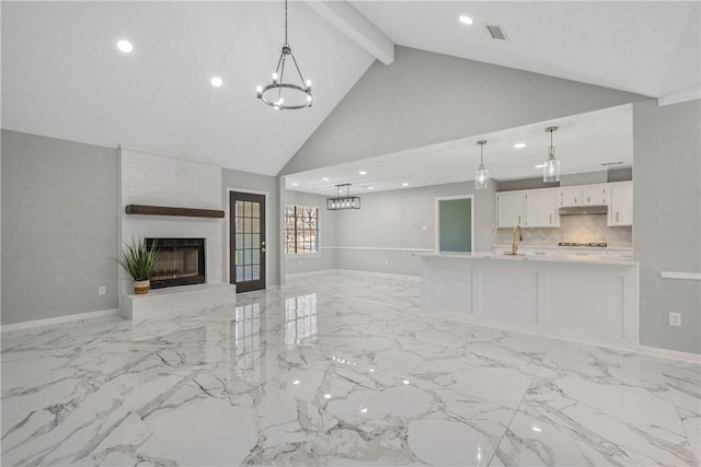 unfurnished living room featuring baseboards, marble finish floor, an inviting chandelier, a fireplace, and a sink