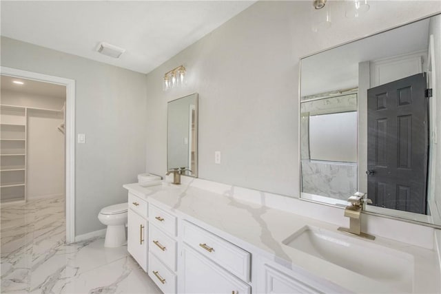 full bath featuring double vanity, toilet, marble finish floor, a walk in closet, and a sink