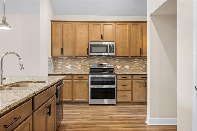 4842 Native Tree Ln, College Station, TX 77845 - kitchen with stainless steel appliances, a sink, light wood-style floors, brown cabinetry, and decorative backsplash