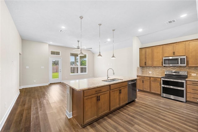 4842 Native Tree Ln, College Station, TX 77845 - kitchen featuring stainless steel appliances, a sink, brown cabinets, tasteful backsplash, and dark wood-style flooring