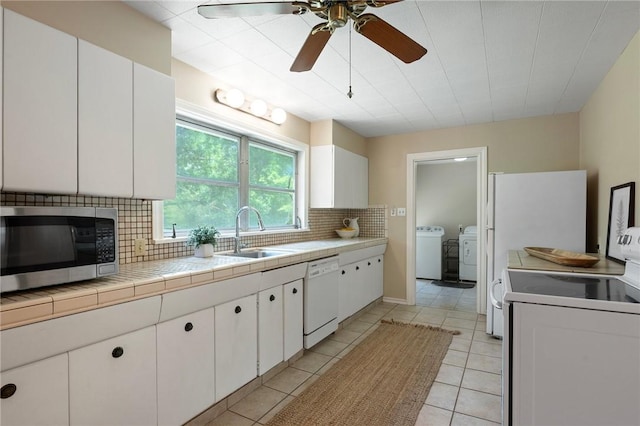 1210 Munson Ave, College Station, TX 77840 - kitchen with white appliances, a sink, washing machine and dryer, backsplash, and white cabinets