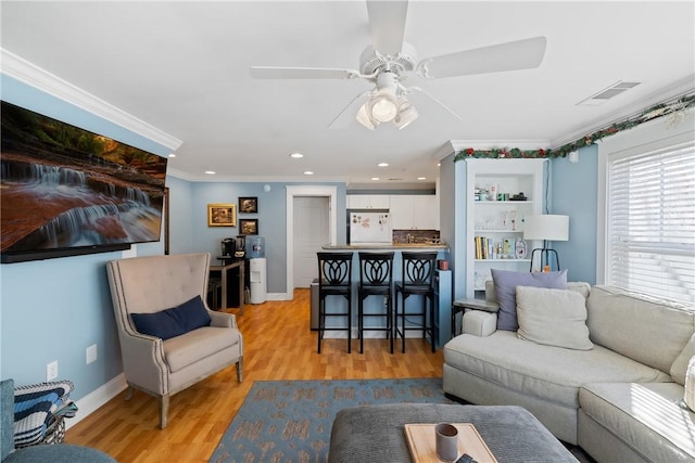 living area featuring ornamental molding, light wood-style floors, baseboards, ceiling fan, and recessed lighting