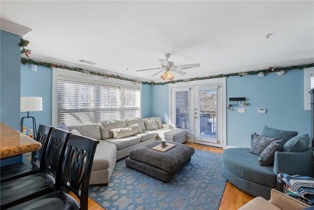 living room featuring wood finished floors, ceiling fan, and crown molding
