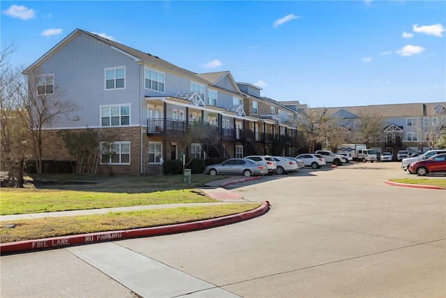 view of building exterior with uncovered parking, a residential view, and stairway