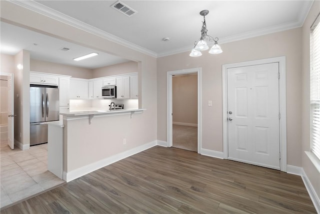 kitchen featuring white cabinets, appliances with stainless steel finishes, kitchen peninsula, and a breakfast bar