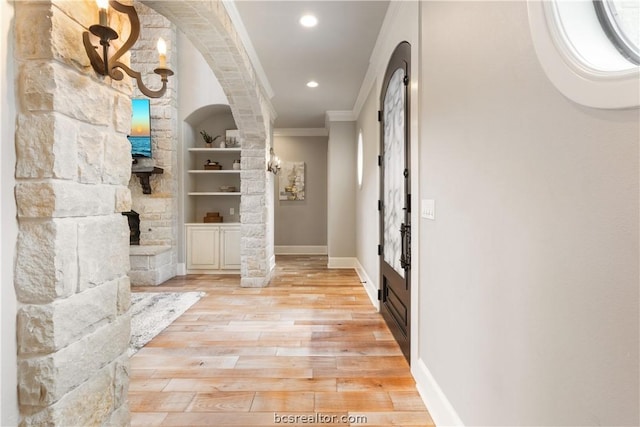 hall featuring built in shelves, light wood-type flooring, and ornamental molding