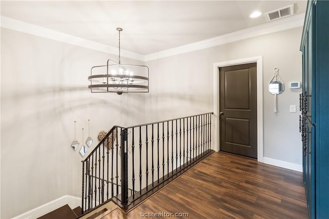 corridor featuring dark hardwood / wood-style flooring, crown molding, and a notable chandelier