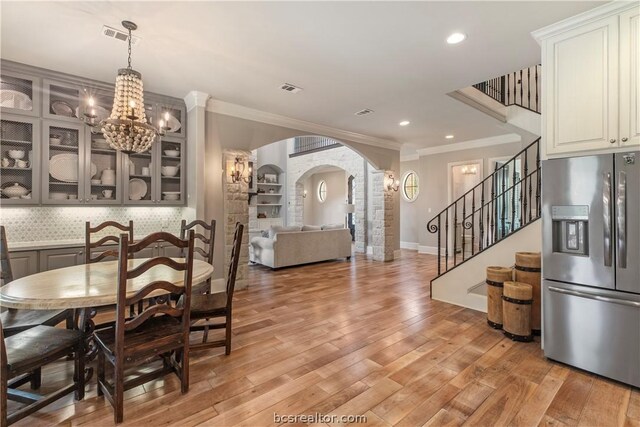 dining room with a chandelier, ornamental molding, and light hardwood / wood-style flooring