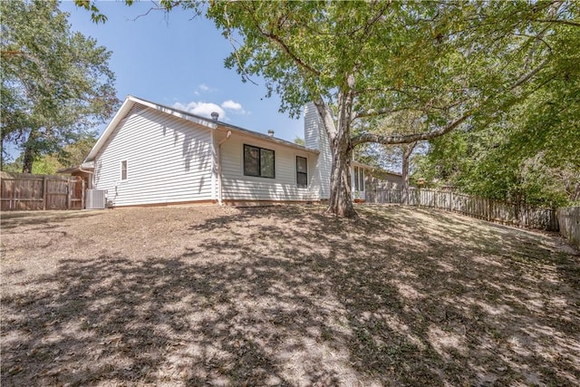 rear view of property featuring cooling unit, a fenced backyard, and a chimney