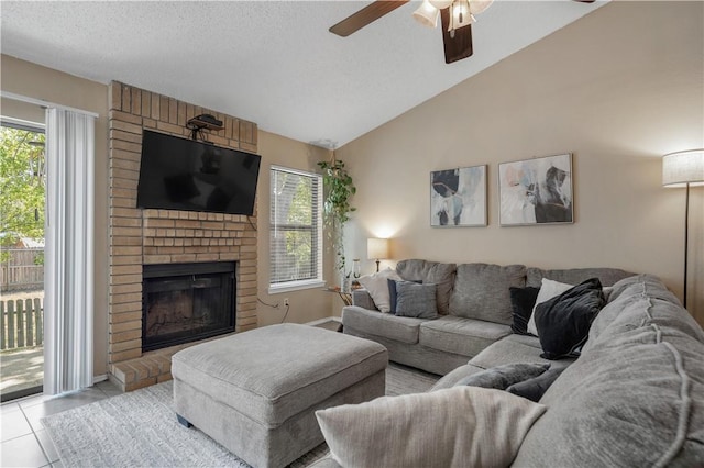 living room with a fireplace, light tile patterned flooring, vaulted ceiling, a textured ceiling, and ceiling fan