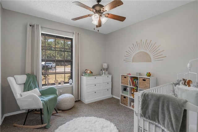 bedroom featuring carpet floors, a ceiling fan, a textured ceiling, a crib, and baseboards