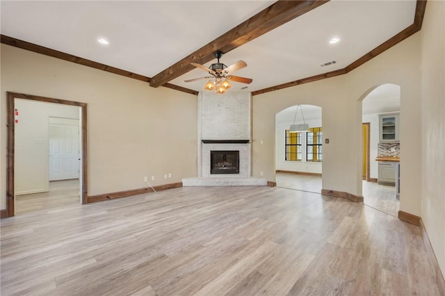 unfurnished living room featuring light wood finished floors, a fireplace, baseboards, and beam ceiling