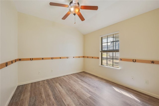 spare room featuring lofted ceiling, ceiling fan, wood finished floors, and baseboards