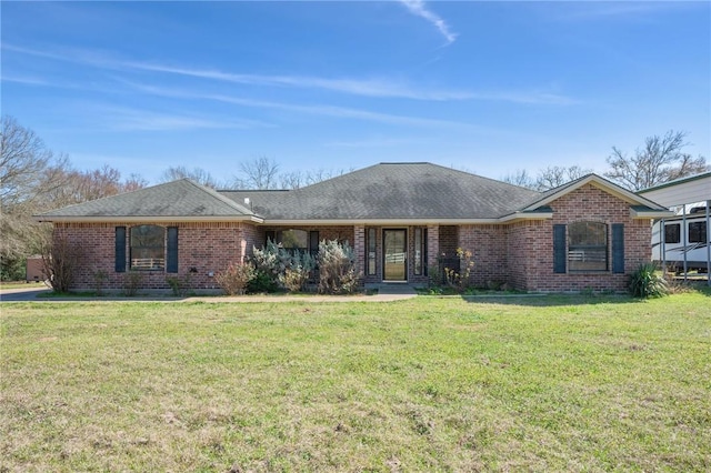 single story home with a shingled roof, a front lawn, and brick siding